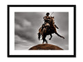 A man riding on top of a rodeo horse next to an art print.