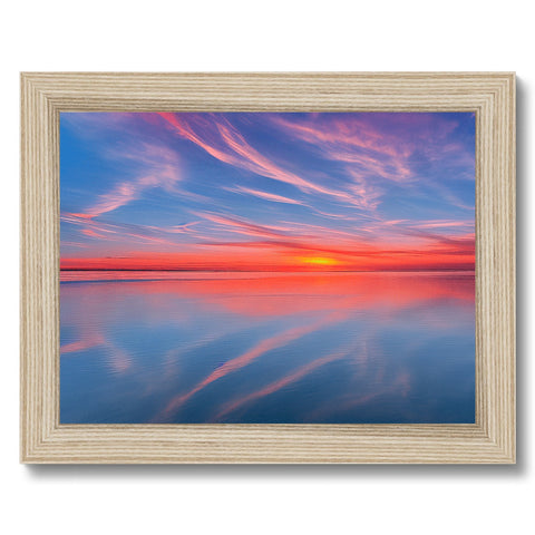A picture of a sunset over a beach on a wooden plate framed in a white background