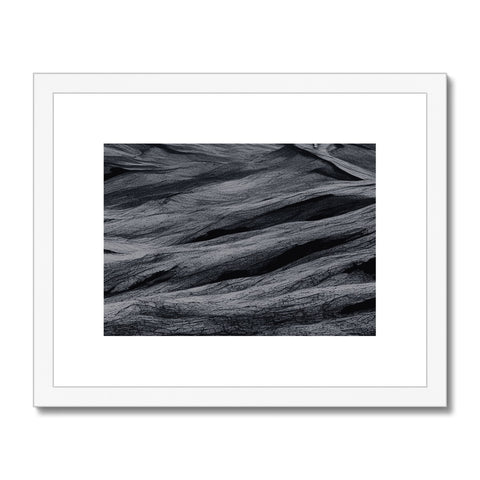 A wooden art print sitting on a beach with a white light colored ocean next to it