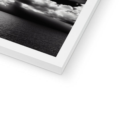 A white photo on top of a folded black book page next to an open photo frame