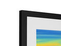 A framed picture of a sunset on a white background hanging on a picture easel.