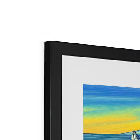 A framed picture of a sunset on a white background hanging on a picture easel.