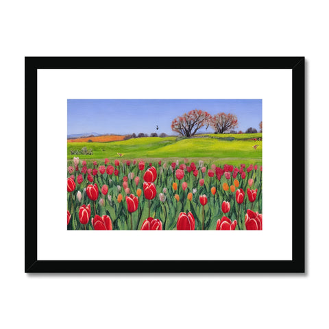 A framed photograph of a field of flowers with tulips growing up on a green field