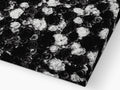 A piece of black fabric on a bed covered in white and blue flower arrangement .