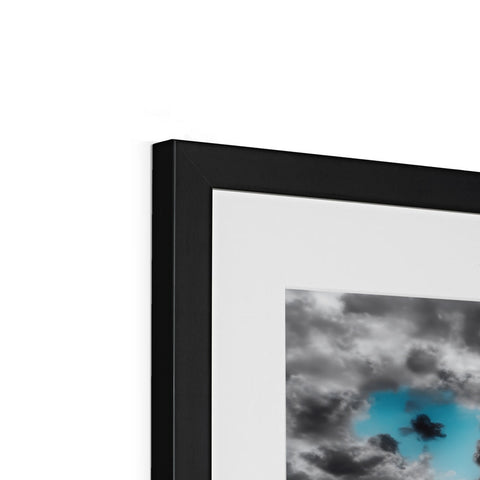 An art print is located on top of a photo frame with a dark cloud behind it
