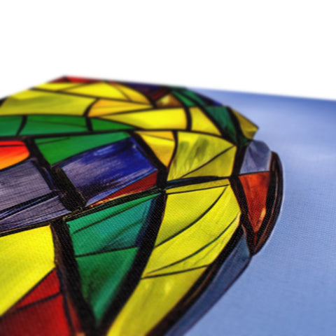 A wooden pillow set in stained glass sitting on a bed underneath a lamp.