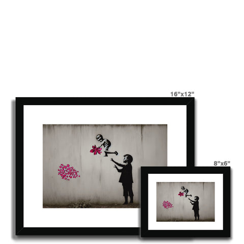 Two black and white pictures surrounded by flowers on a wall.