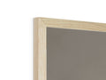 A picture frame sitting on top of a wooden table is reflected against a white wall.