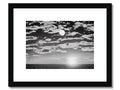 A wooden framed photo of a black and white sunset on a dark beach.