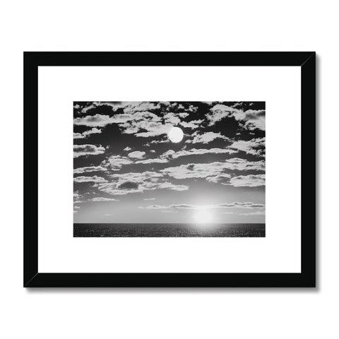 A wooden framed photo of a black and white sunset on a dark beach.