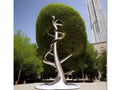 A large metal sculpture on top of a grassy hill topped with a tree on the