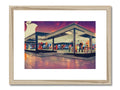 A gas station is displayed next to a shopping plaza next to an art print.