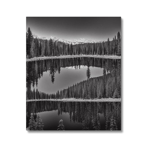 A black and white picture framed by two lakes near a forest of a mountain.
