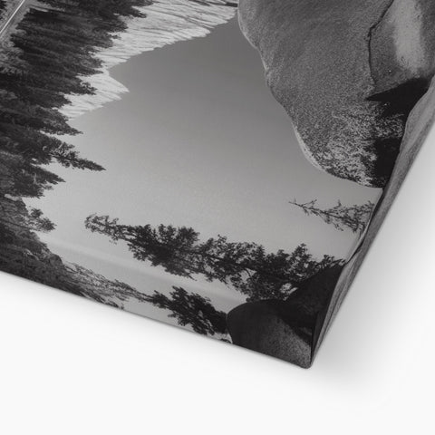 A mirror on a picture table in the woods next to a mountain covered in snow.