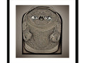 An angry face on a framed wall next to a coin purse holder.