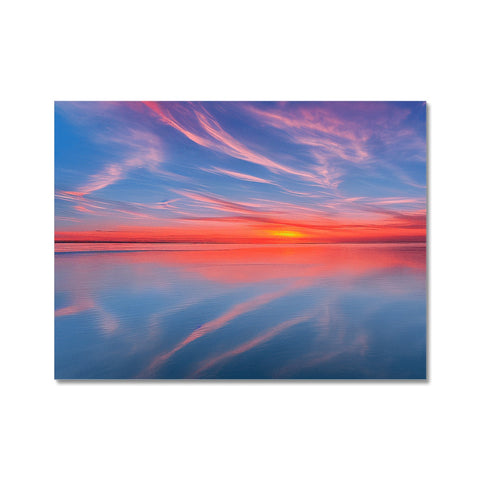 A view of the ocean on a blanket with a sunset set against a blue sky.