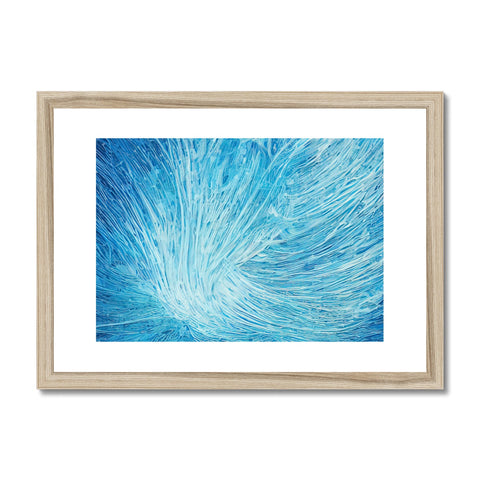A framed art print on blue paper with green feathers on it.