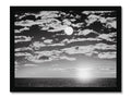 a large framed photo of sun setting over the ocean next to a dark moon