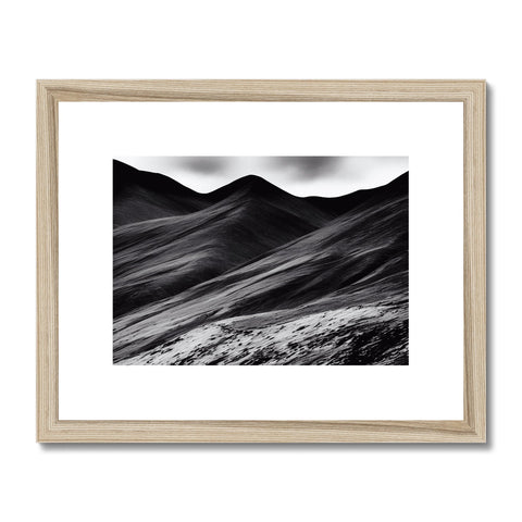 A black and white photo on a wood frame against a flat desert landscape.