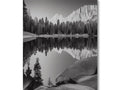 A mirror image of a lake in a black and white photo frame on a wall.