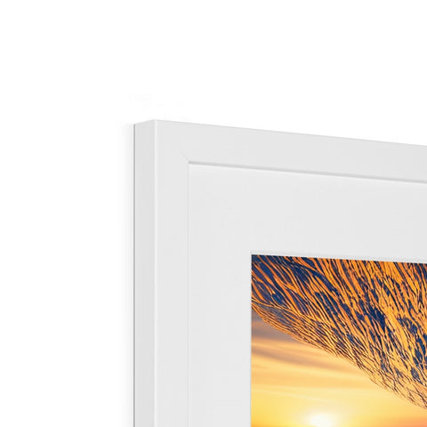 A picture frame with a picture of a sunset on it is in it.