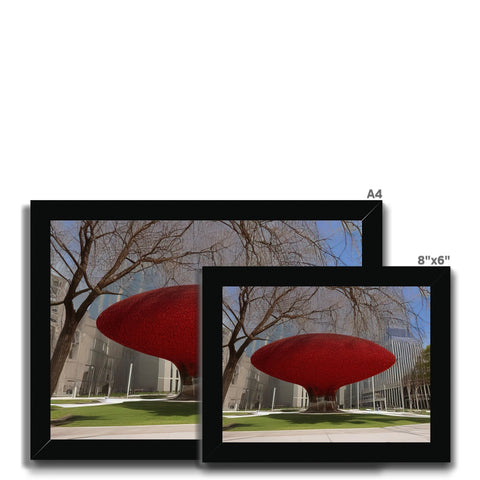 A large red picture frame sits on a large flat screen television table next to a couch
