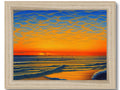 A photo of waves and a sunset on a blue canvas framed in wood.