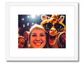 A giraffe and some people standing in a field looking at a picture and sitting next