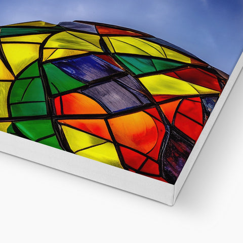 A rainbow kite flying on a stained glass roof.