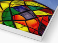 A rainbow kite in a white kite holder with a windowed glass background.