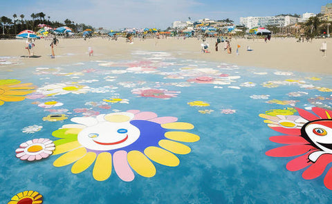 A water filled beach with flowers laying on a beach that has umbrellas on it
