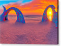 An archway on a sandy beach in the dark with a colorful sunset