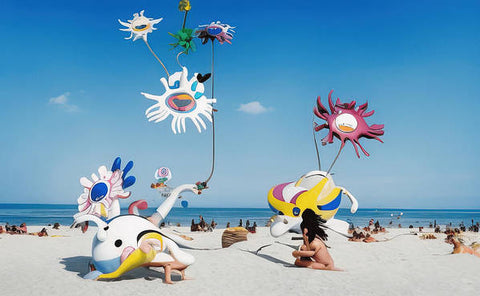 A beach is decorated with many sunbathers and umbrellas on the sand