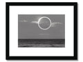 An art print of a black and white full moon lit up over a moonlit ocean
