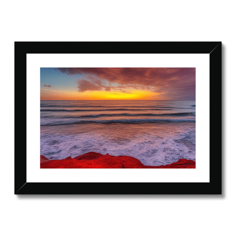 An art print with a photo of a red beach and clouds near a rocky cliff.