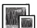 Art print of pine trees hanging on a wall with glass and black paper.