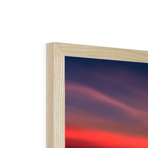 A wood framed photo with a large framed picture of a sunset in front of it.