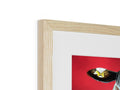 A big white framed picture of a red bird sitting on top of a piece of artwork
