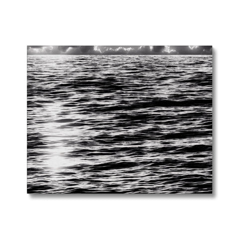 A black and white photo of cloudy waters with white blurring and red sunset.