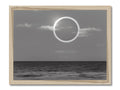A silver and black framed photograph shows an eclipse happening in the sky and silver.