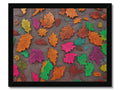 A colorful blanket hanging on a wall is covered in autumn leaves.