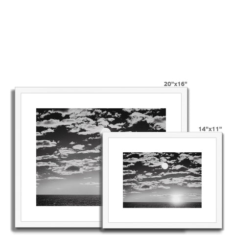 A white photograph of a sunset on a black and white picture frame.