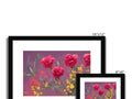 A picture printed framed picture of flowers on a white wall of several different types.