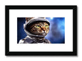 A cat sitting on a desk with a black and white framed picture of an astronaut.
