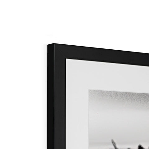 A picture frame with a black and white photo placed under a white backdrop to a glass