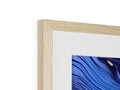 A long wooden piece of art is hanging behind a framed photo of an ocean.
