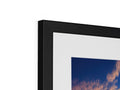 A white picture frame on top of a black framed photo.
