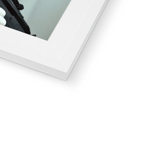 A white picture frame sits on top of a mirror holding a picture.