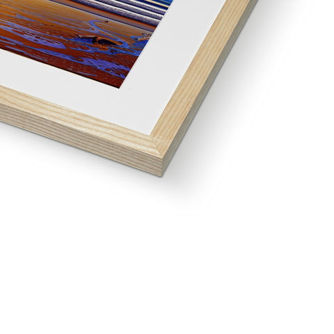an art print in a white frame sitting on a table on a wooden wooden surface.