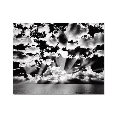 A black and white art print with a sun reflecting down from a cloud over clouds.